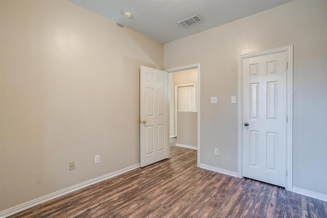 unfurnished bedroom featuring baseboards, visible vents, and dark wood finished floors