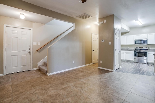 interior space featuring light tile patterned floors, stairway, visible vents, and baseboards