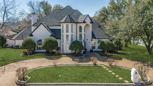 french country style house featuring a chimney and a front yard