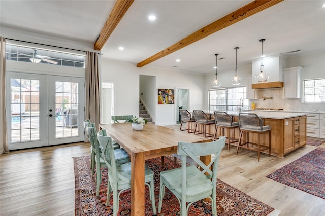 dining space with beam ceiling, plenty of natural light, french doors, and light wood-type flooring