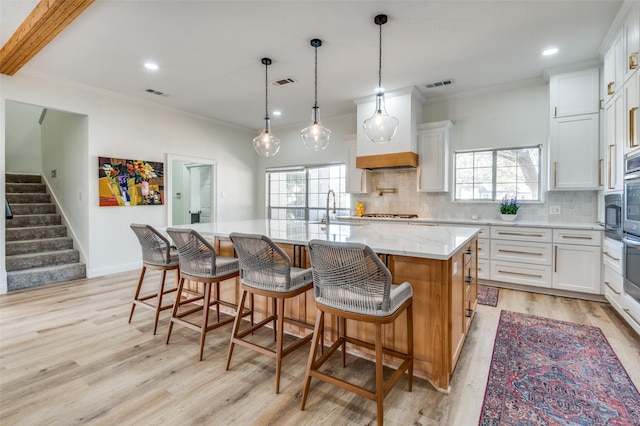 kitchen featuring light wood-type flooring, visible vents, and backsplash