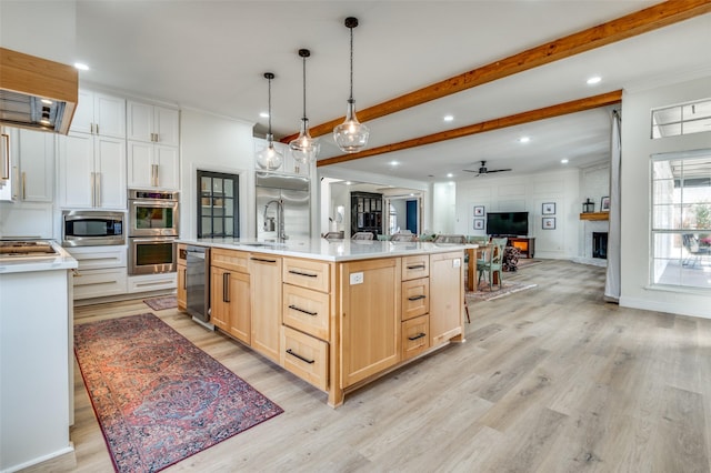 kitchen with light brown cabinetry, beamed ceiling, open floor plan, light countertops, and appliances with stainless steel finishes