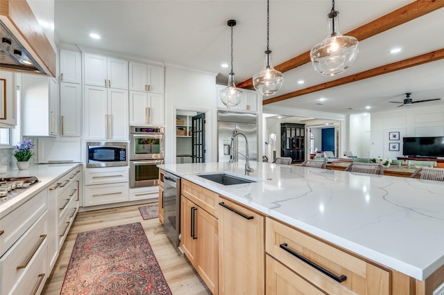 kitchen with open floor plan, built in appliances, light wood-type flooring, custom range hood, and a sink