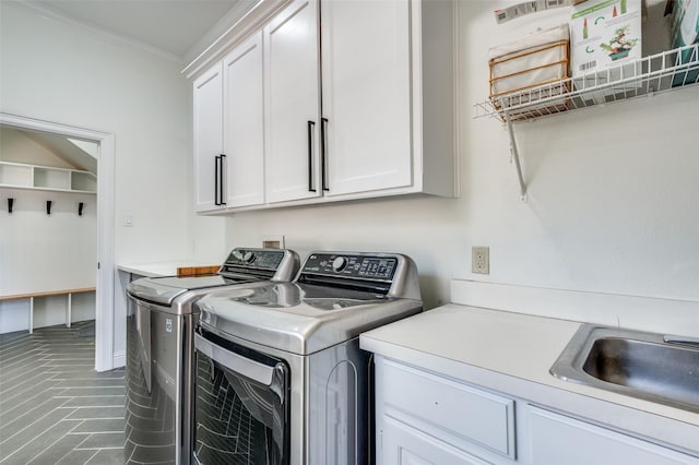 washroom featuring a sink, crown molding, cabinet space, and washer and clothes dryer