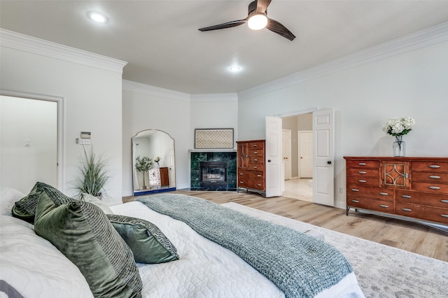 bedroom with a ceiling fan, recessed lighting, a fireplace, crown molding, and light wood-type flooring