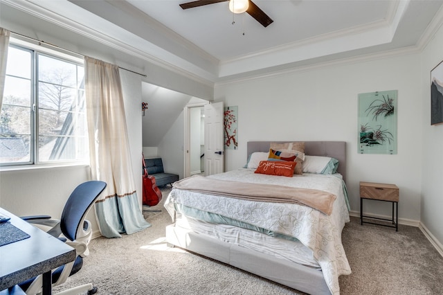 carpeted bedroom with a raised ceiling, a ceiling fan, baseboards, and ornamental molding