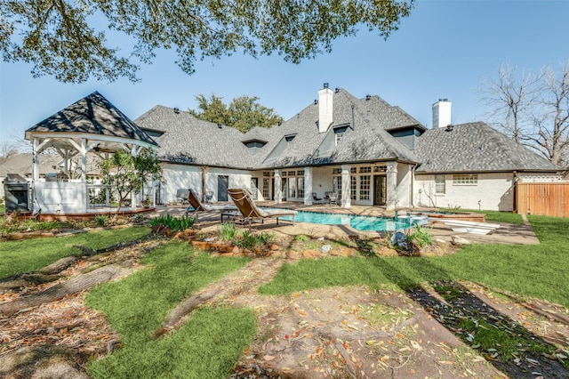 rear view of house with a fenced in pool, fence, a chimney, french doors, and a patio area