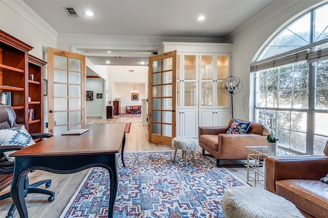 office space with wood finished floors, french doors, visible vents, and ornamental molding