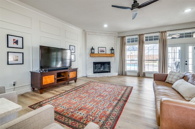 living area featuring light wood-type flooring, a ceiling fan, a wealth of natural light, and crown molding