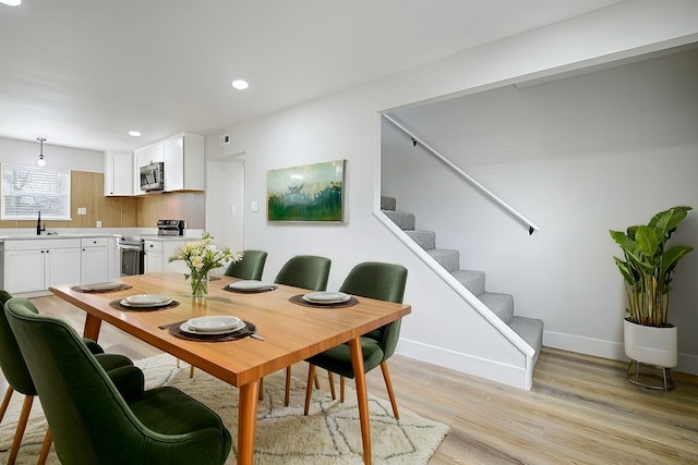 dining room featuring light wood finished floors, recessed lighting, visible vents, stairway, and baseboards