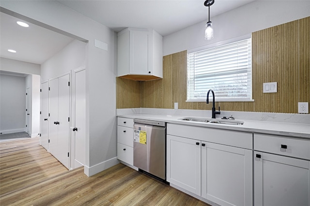 kitchen featuring a sink, light wood finished floors, light countertops, and stainless steel dishwasher