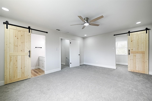 unfurnished bedroom featuring a barn door, visible vents, carpet flooring, and recessed lighting