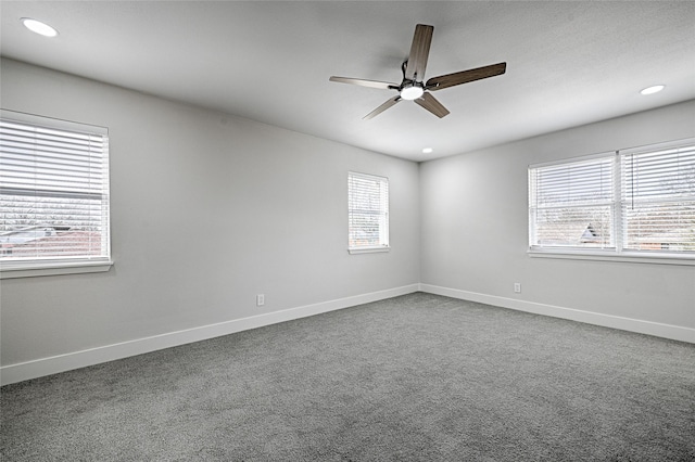 unfurnished room with dark colored carpet, ceiling fan, and baseboards