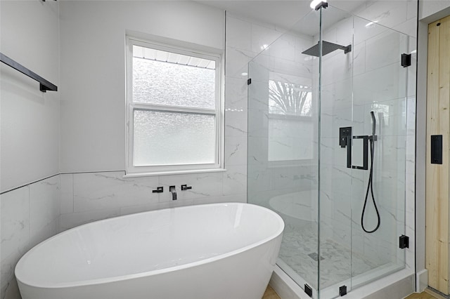 full bath featuring a freestanding tub and a marble finish shower