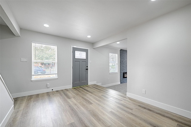 entryway featuring a large fireplace, light wood-style flooring, baseboards, and recessed lighting