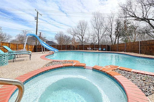 view of swimming pool featuring a pool with connected hot tub, a water slide, a fenced backyard, and a patio