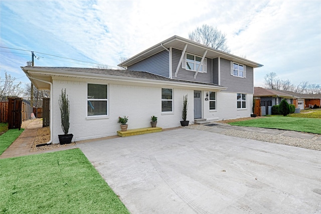 view of front of property featuring a front lawn, a patio area, fence, and brick siding