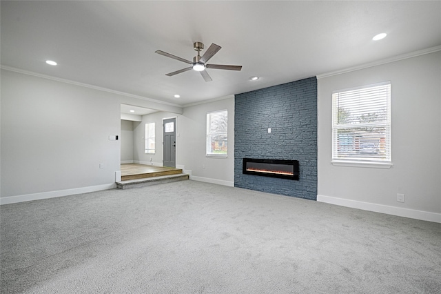 unfurnished living room featuring a large fireplace, baseboards, a wealth of natural light, and crown molding