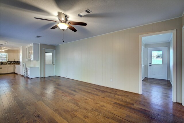 unfurnished living room featuring dark wood-style floors, a wealth of natural light, visible vents, and a ceiling fan