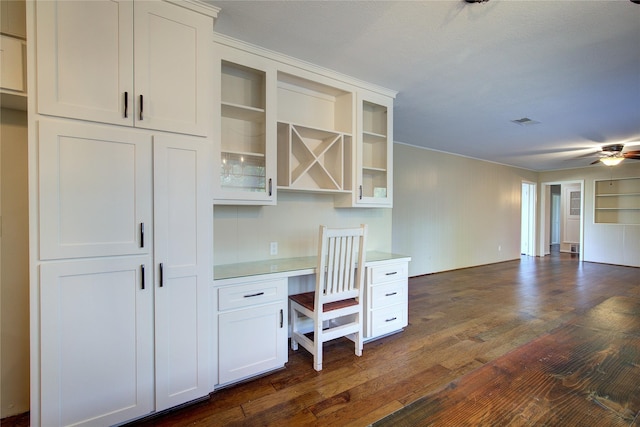 unfurnished office with ceiling fan, visible vents, dark wood-type flooring, and built in study area