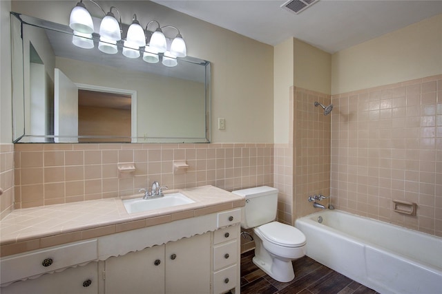 bathroom featuring tile walls, visible vents, shower / bathing tub combination, toilet, and wood finished floors