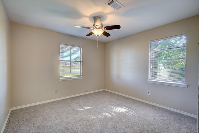 carpeted spare room with a healthy amount of sunlight, visible vents, and baseboards