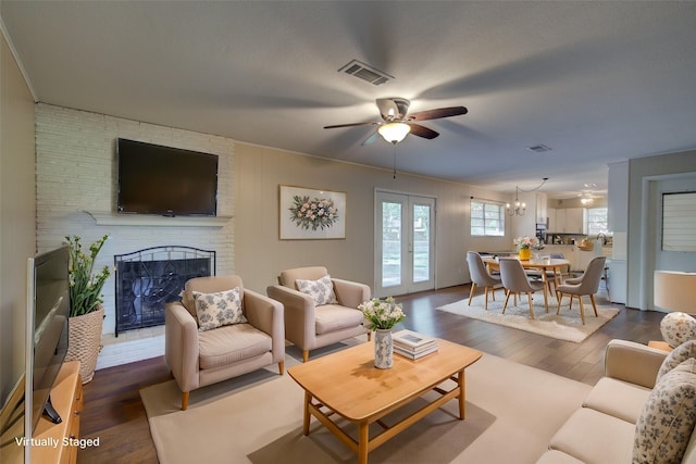 living area featuring french doors, a brick fireplace, wood finished floors, and visible vents