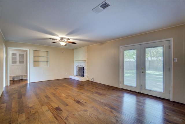 unfurnished living room with hardwood / wood-style flooring, a brick fireplace, visible vents, and built in features