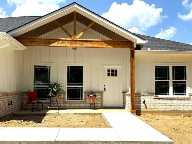 property entrance with brick siding and a shingled roof