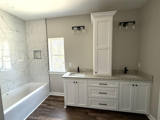 bathroom featuring double vanity, wood finished floors, and a sink