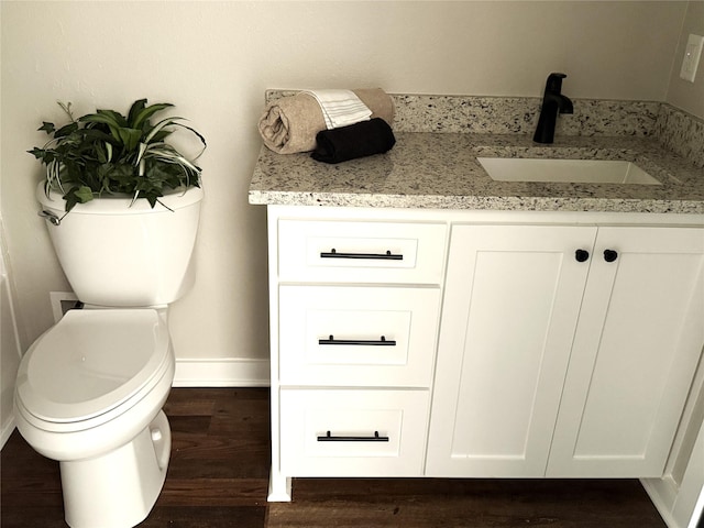 bathroom with wood finished floors, toilet, baseboards, and a sink
