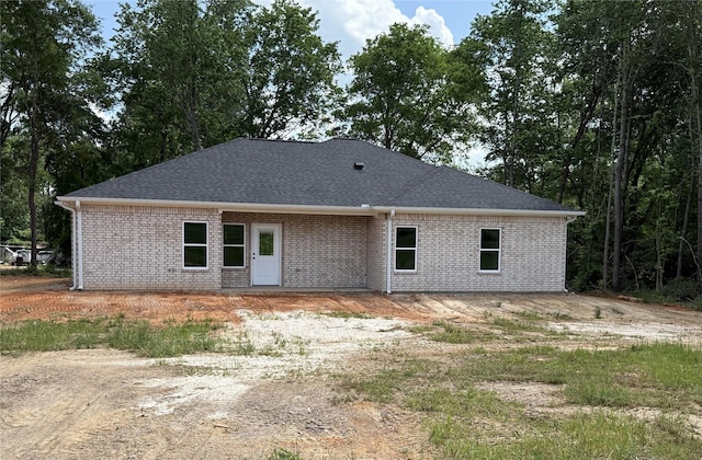 back of property with roof with shingles and brick siding