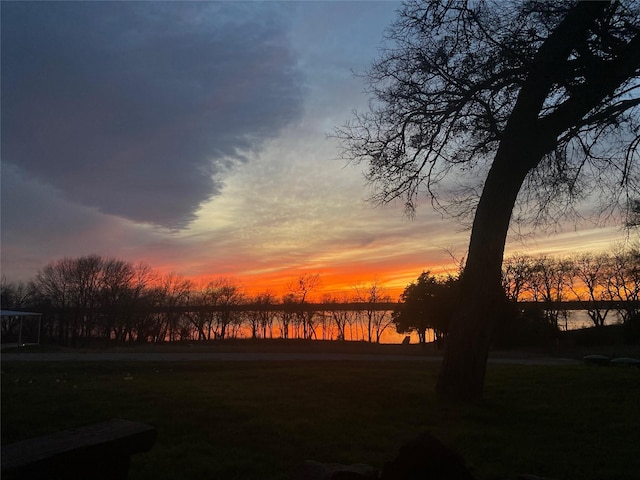 yard at dusk featuring a water view