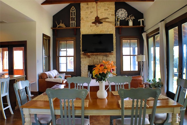 dining space with lofted ceiling, french doors, plenty of natural light, and a stone fireplace