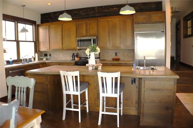 kitchen with a sink, stainless steel appliances, tasteful backsplash, and a kitchen island