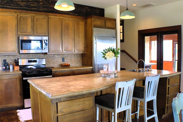 kitchen with french doors, stainless steel appliances, backsplash, a kitchen island with sink, and a sink