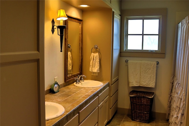 bathroom with double vanity, tile patterned flooring, a sink, and baseboards