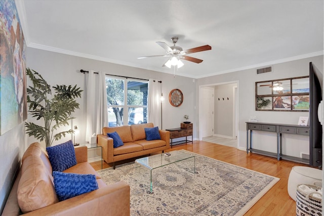 living room featuring baseboards, visible vents, ceiling fan, wood finished floors, and crown molding