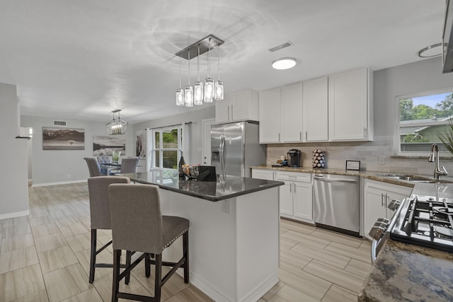 kitchen with tasteful backsplash, visible vents, appliances with stainless steel finishes, a kitchen breakfast bar, and a sink