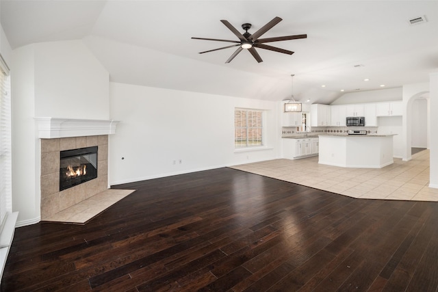 unfurnished living room with lofted ceiling, light wood-style floors, a fireplace, and visible vents