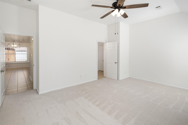 carpeted spare room with lofted ceiling, ceiling fan with notable chandelier, visible vents, and baseboards