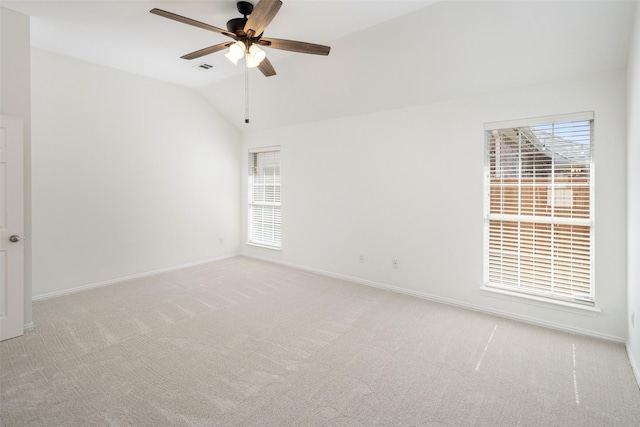 spare room with baseboards, vaulted ceiling, a ceiling fan, and light colored carpet