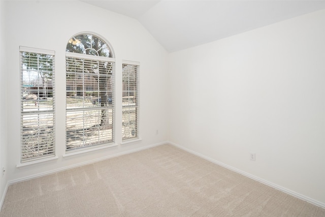 carpeted empty room with lofted ceiling and baseboards