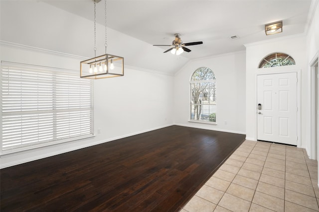 entryway with baseboards, a ceiling fan, ornamental molding, wood finished floors, and vaulted ceiling