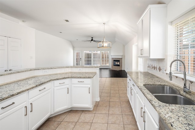 kitchen with light tile patterned floors, tasteful backsplash, ceiling fan, a fireplace, and a sink