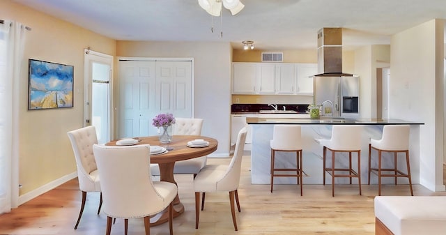 dining space with light wood-type flooring, visible vents, and baseboards