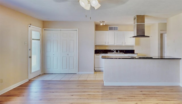 kitchen featuring visible vents, white cabinets, dishwasher, wall chimney exhaust hood, and dark countertops