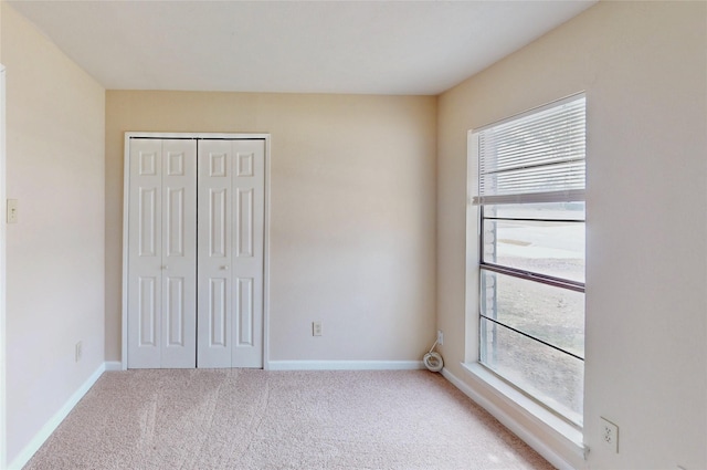 unfurnished bedroom with carpet floors, multiple windows, and baseboards