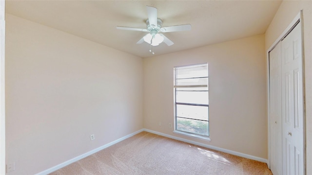 unfurnished bedroom featuring light carpet, a closet, a ceiling fan, and baseboards