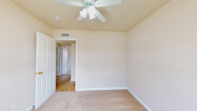 spare room with baseboards, visible vents, ceiling fan, and light colored carpet